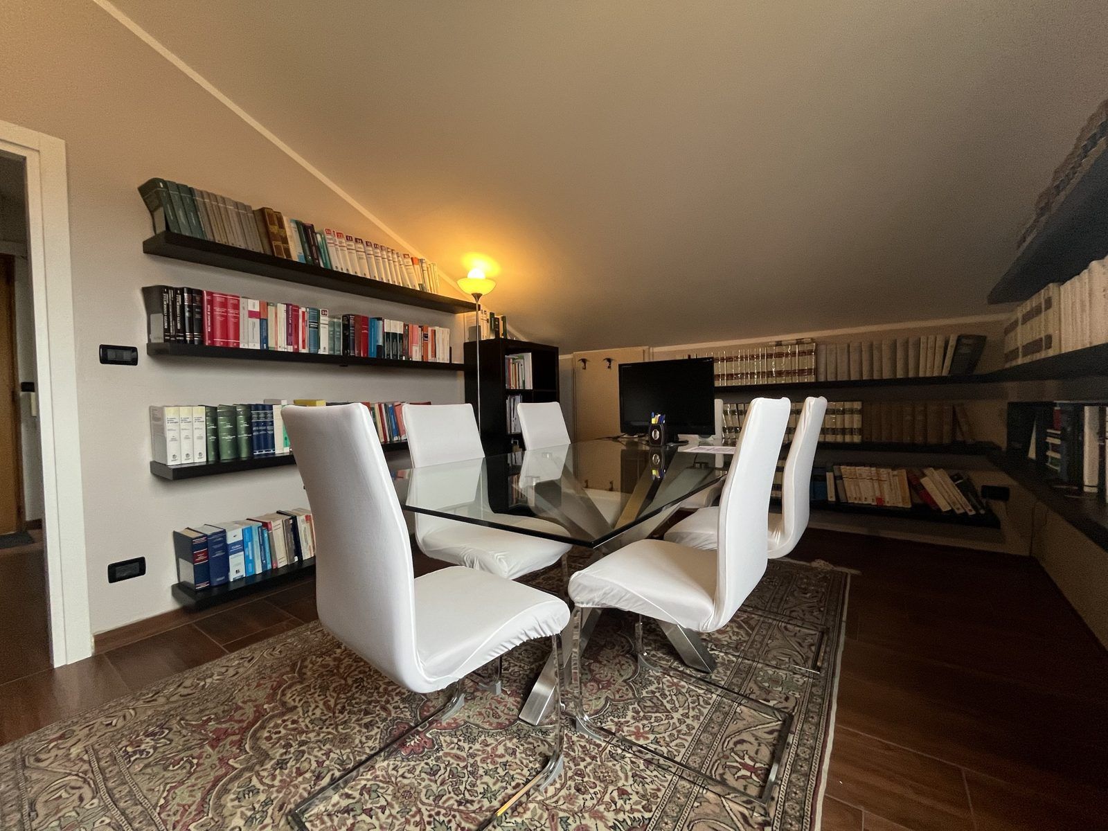 Sala riunioni dello studio con libreria e tavolo in vetro